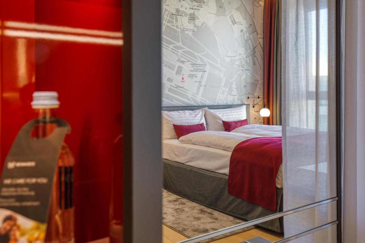 Intercityhotel Berlin Airport Ber Terminal 1 & 2 Schönefeld Eksteriør bilde The photo shows a modern hotel room that features a comfortable bed with white linens and a red accent blanket. Behind the bed is a stylish wall displaying a map design. The room has large windows dressed with light-colored curtains, allowing natural
