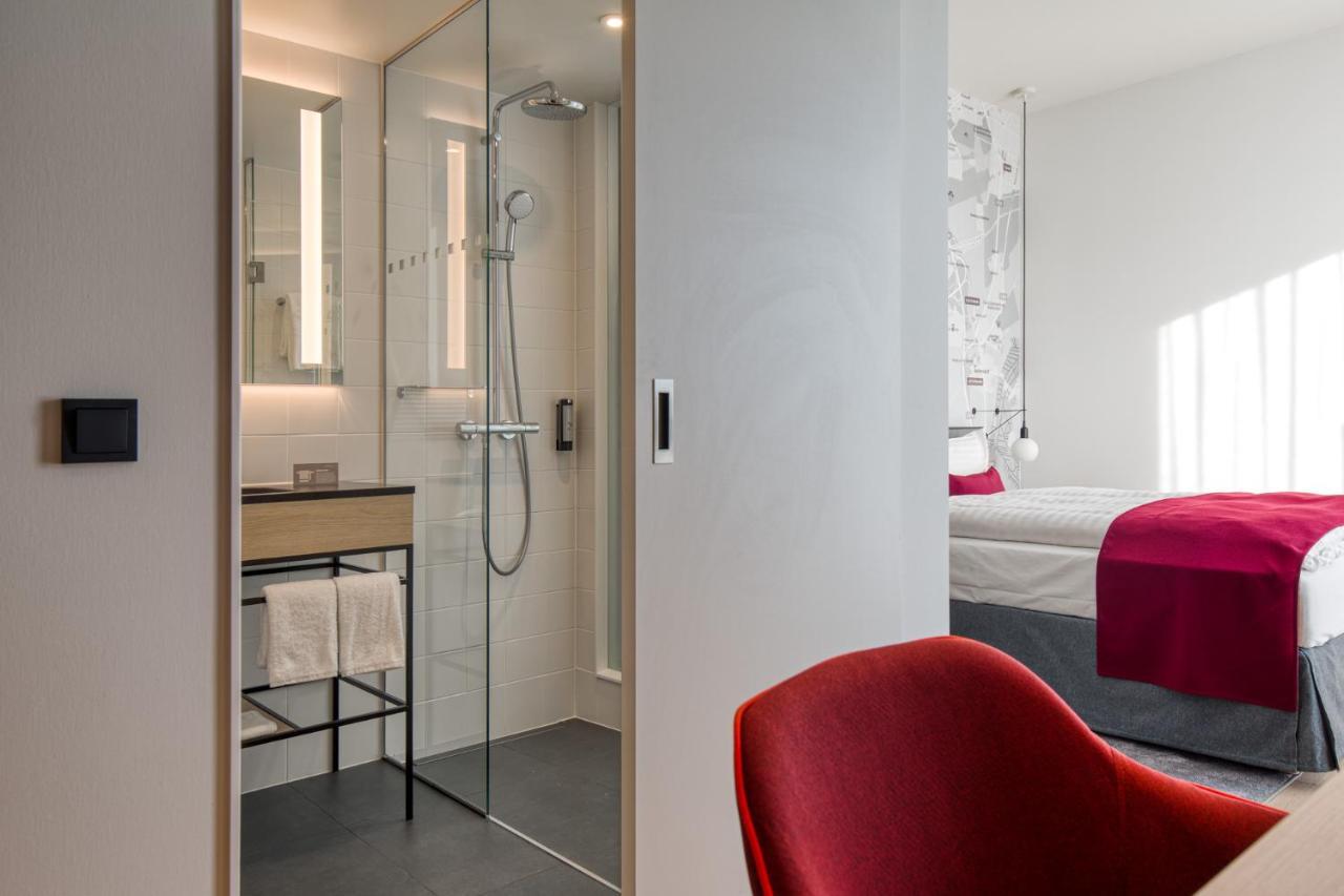 Intercityhotel Berlin Airport Ber Terminal 1 & 2 Schönefeld Eksteriør bilde The photo shows a modern hotel room or bathroom space. On the left, there is a glass-enclosed shower area with a sleek design, featuring a showerhead and minimalist fixtures. Adjacent to the shower, there's a sink area with a stylish countertop and a